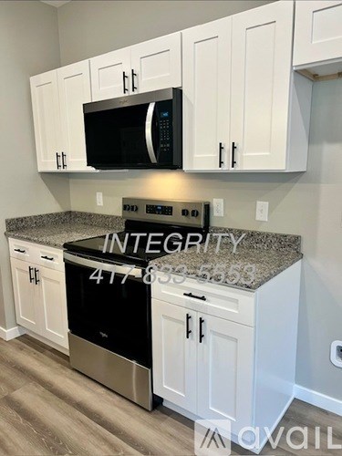 A kitchen with white cabinets and a black microwave above the stove.