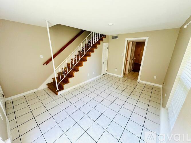 A spacious room with a staircase and tiled flooring.