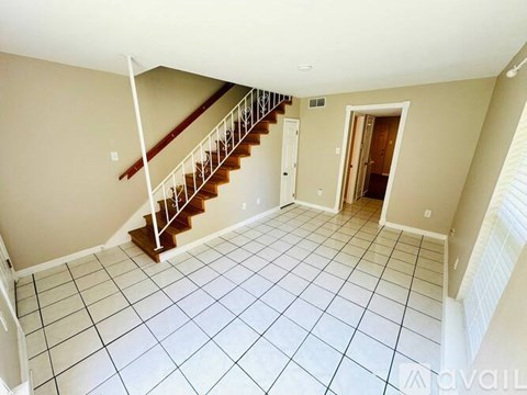 A spacious room with a staircase and tiled flooring.