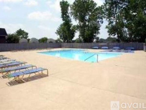 A pool with sun loungers and trees in the background.