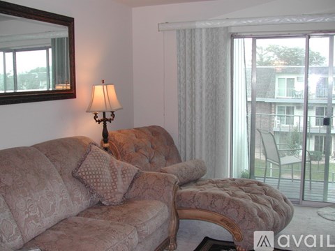 A living room with a couch, a lamp, and a large window.