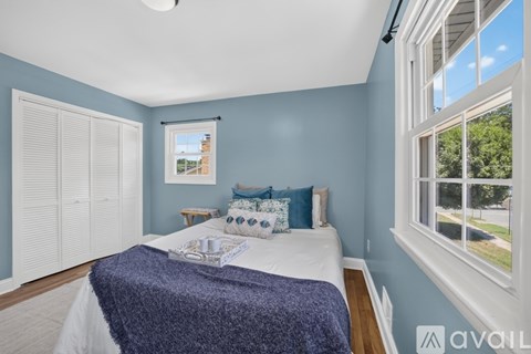 A bedroom with a bed, pillows, and a window.