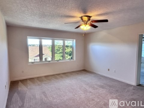 A room with a ceiling fan and a window overlooking a yard.