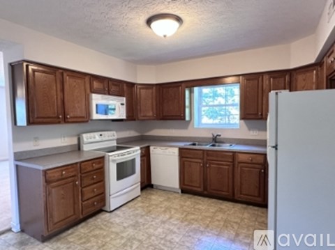 A kitchen with brown cabinets and white appliances.