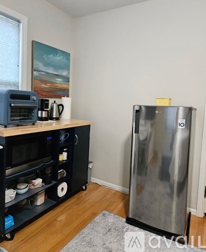 A kitchen with a stainless steel refrigerator and a wooden shelf with various items on it.
