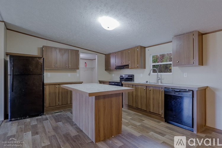 A kitchen with wooden cabinets and a black fridge.