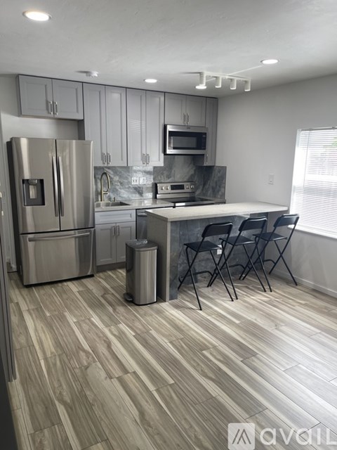 A kitchen with a refrigerator, sink, and a dining table with chairs.