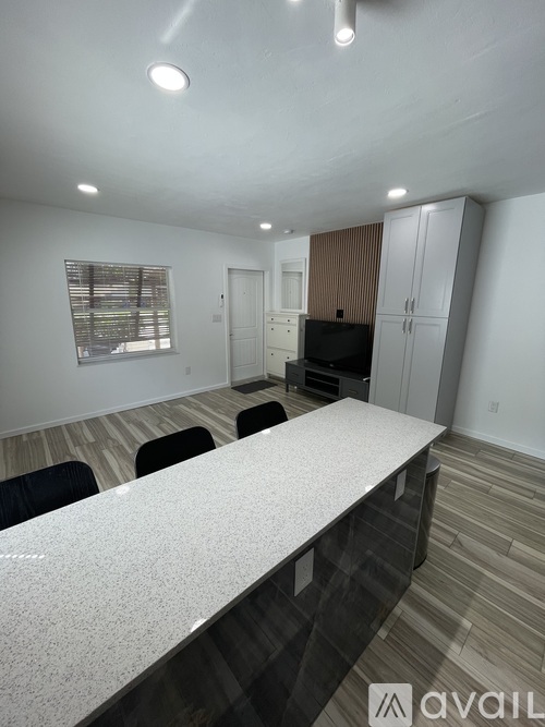A kitchen with a white countertop and black chairs.