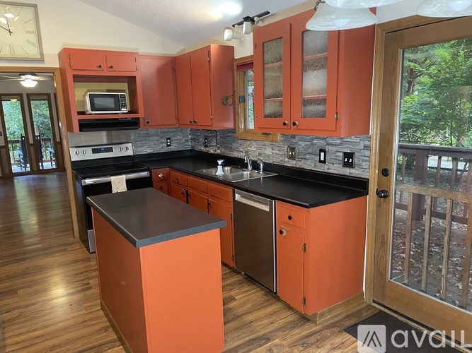 A kitchen with orange cabinets and a black countertop.