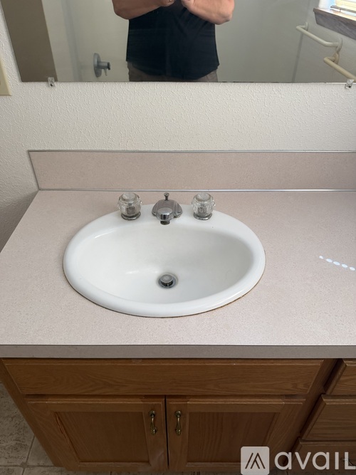 A person is taking a selfie in a bathroom with a white sink and a mirror.