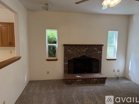 A living room with a fireplace and a ceiling fan.