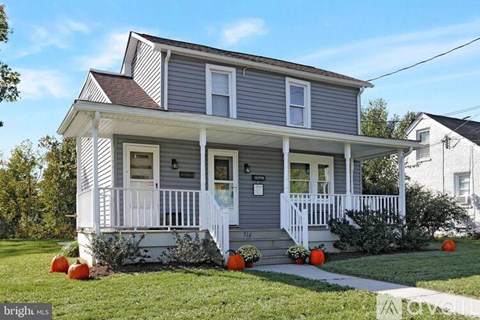A two-story house with a grey and white exterior and a porch.