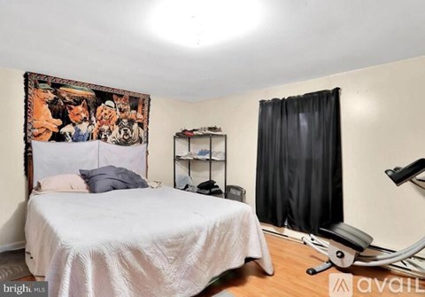 A bedroom with a bed, a chair, and a tapestry on the wall.