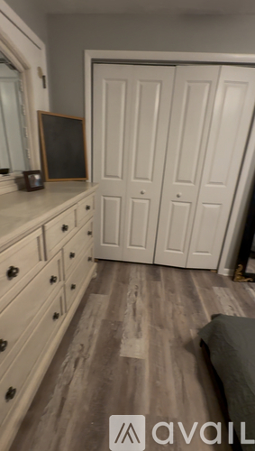 A room with a couch, a mirror, and a wooden floor.
