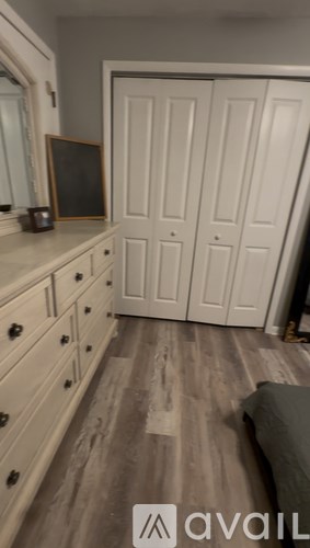 A room with a couch, a mirror, and a wooden floor.