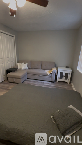 A bedroom with a bed, couch, and a fan.