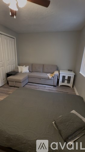 A bedroom with a bed, couch, and a fan.