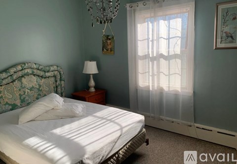 A bedroom with a bed, nightstand, lamp, and a chandelier.
