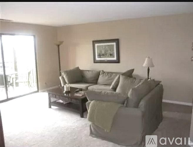 A living room with a grey couch and a picture frame on the wall.