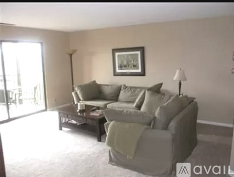 A living room with a grey couch and a picture frame on the wall.