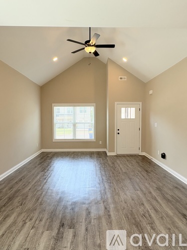 A room with a ceiling fan and wooden flooring.