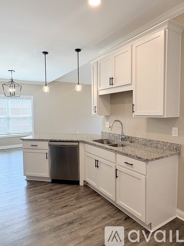 A kitchen with white cabinets and a granite countertop.