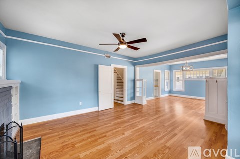 A spacious room with a fireplace and a ceiling fan.
