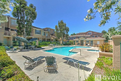 A pool surrounded by chairs and trees in a sunny day.