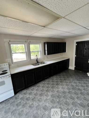 A kitchen with black cabinets and a white dishwasher.