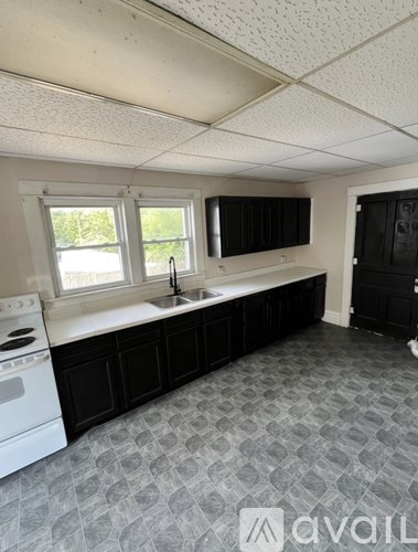 A kitchen with black cabinets and a white dishwasher.
