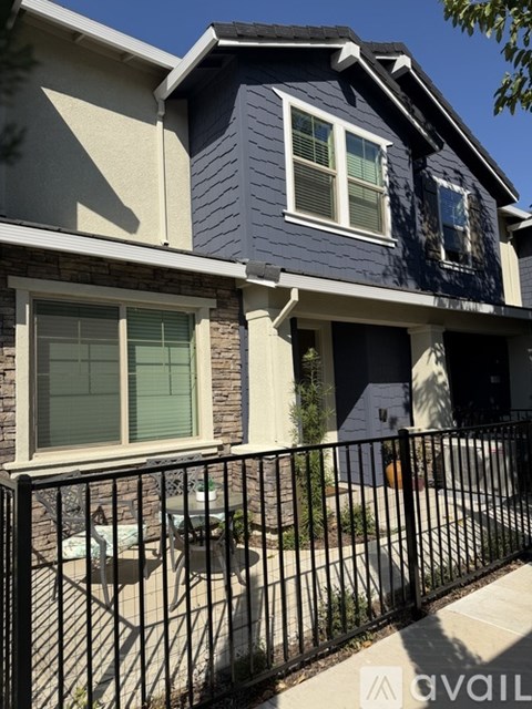 A blue house with a black fence and a white window.