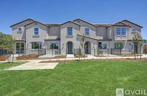 A large, modern house with a front yard and a fence.