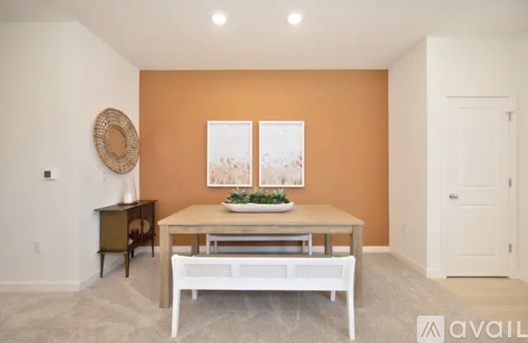 A dining room with a white bench and a table with a bowl of fruit on it.