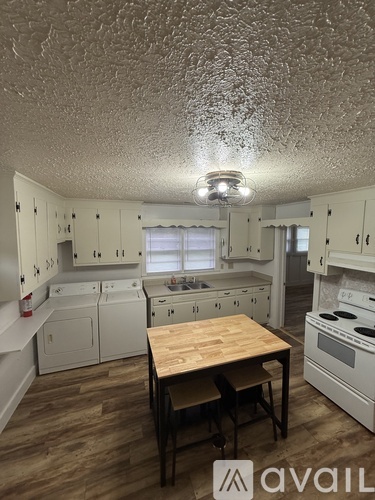 A kitchen with white cabinets and a wooden table.