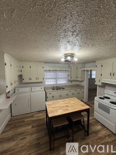 A kitchen with white cabinets and a wooden table.