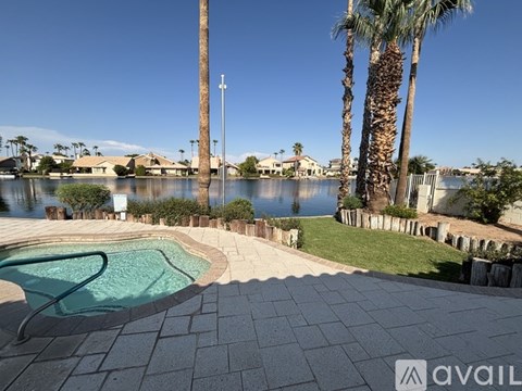 A pool surrounded by palm trees and a stone wall.