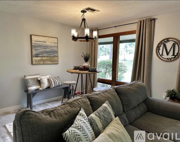 A living room with a grey couch and a painting on the wall.