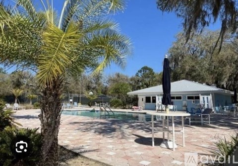 A pool area with a table and chairs and a house in the background.