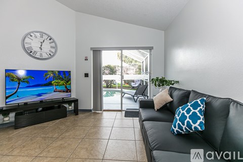 A living room with a black couch and a flat screen TV.