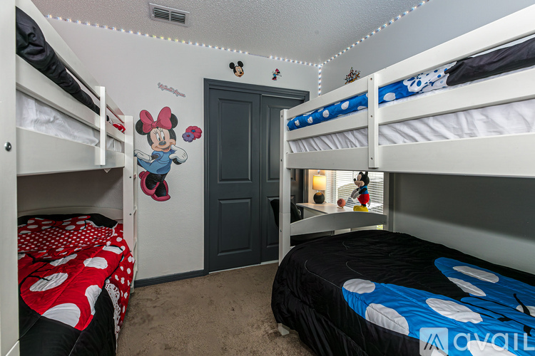 A bedroom with bunk beds and a Minnie Mouse decoration on the wall.