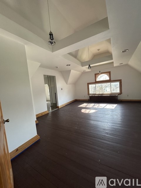 A spacious room with wooden floors and a skylight.