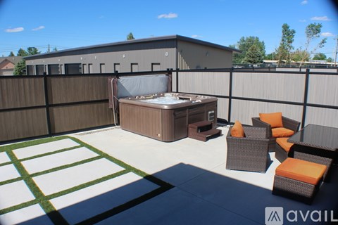 A patio with a hot tub and chairs.