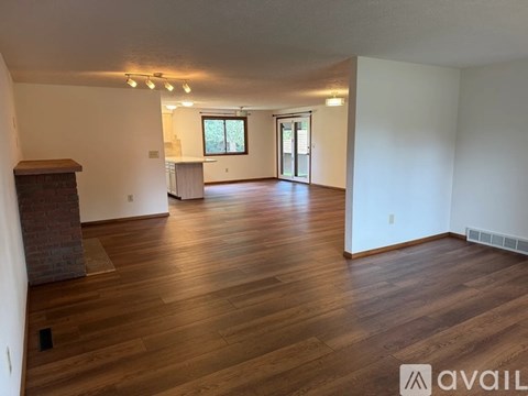 A spacious room with wooden floors and a brick fireplace.