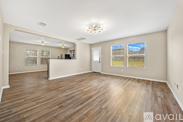 A spacious room with wooden flooring and a large window.