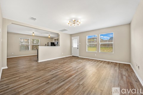 A spacious room with wooden flooring and a large window.
