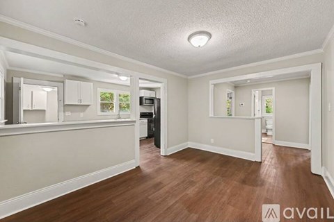 A spacious room with wood flooring and white walls.