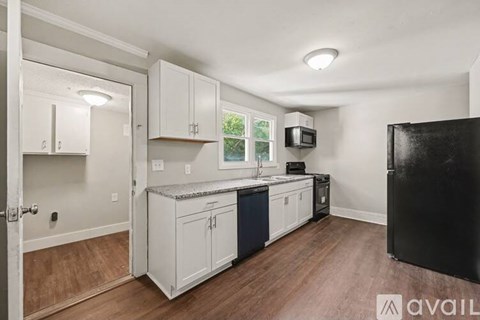A kitchen with white cabinets and a black refrigerator.