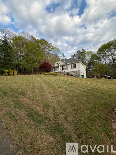 A house is situated in a grassy field with trees in the background.