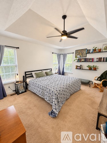 A bedroom with a bed, a ceiling fan, and a bookshelf.