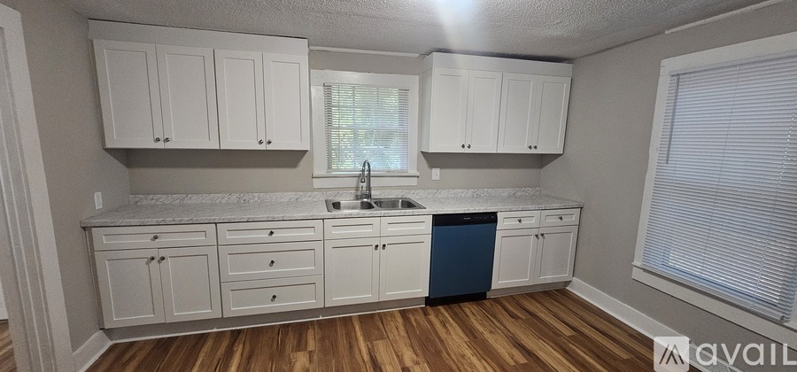 A kitchen with white cabinets and a blue trash can.